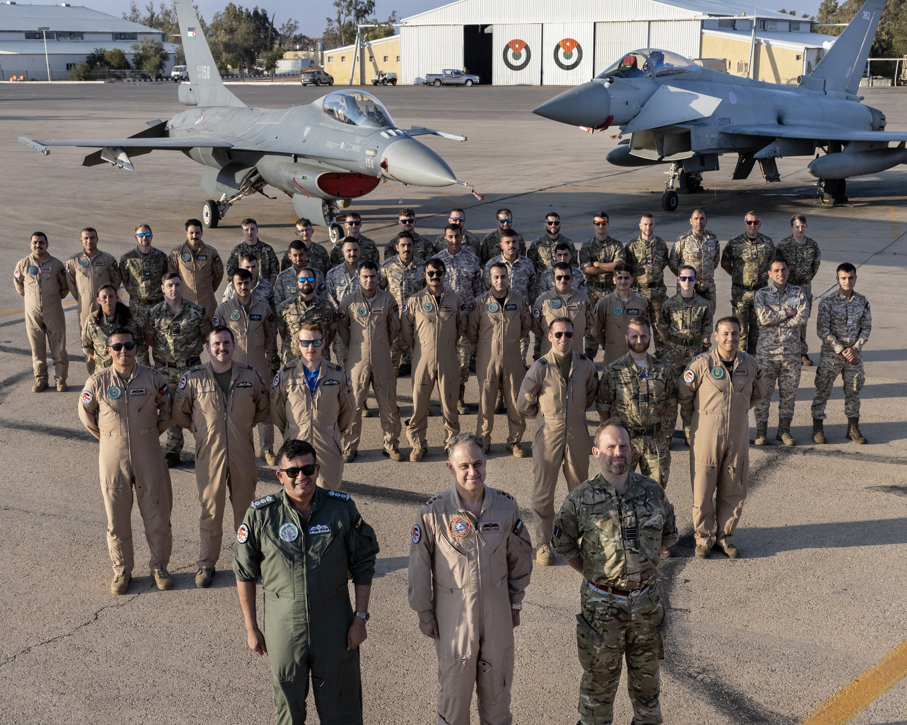 Image shows RAF Typhoon Squadron standing in a triangle formation by two Typhoons on the airfield.